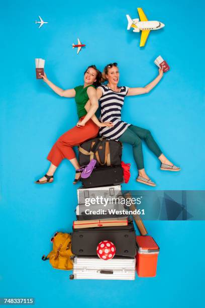 friends sitting on pile of luggage waiting for departure, holding passports and tickets - offbeat documentation stock pictures, royalty-free photos & images