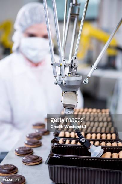 woman in factory looking at robot handling cookies - food and drink industry ストックフォトと画像