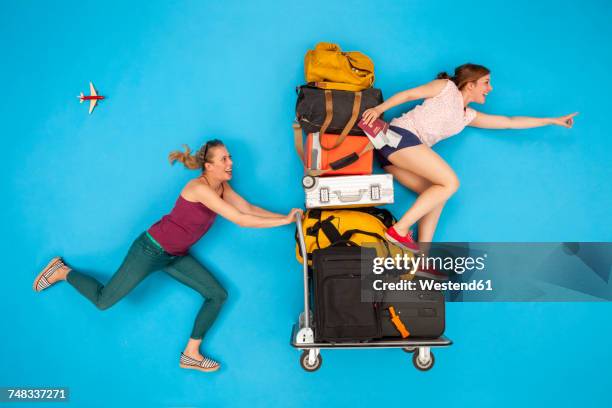 friends pushing luggage trolley, hurrying for departure - luggage trolley stockfoto's en -beelden