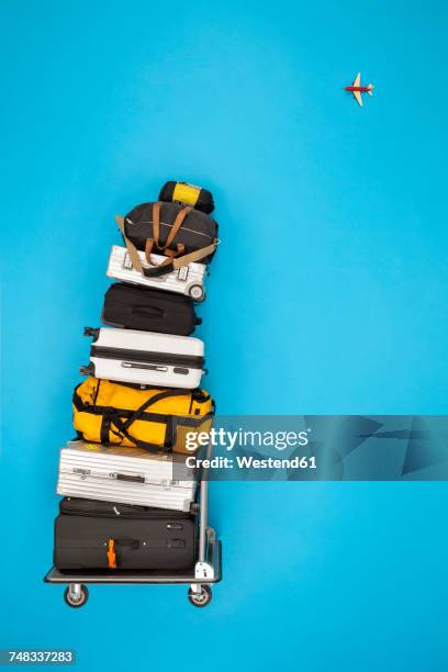 stacked luggage and plane flying in the sky - carrito-para-equipaje fotografías e imágenes de stock