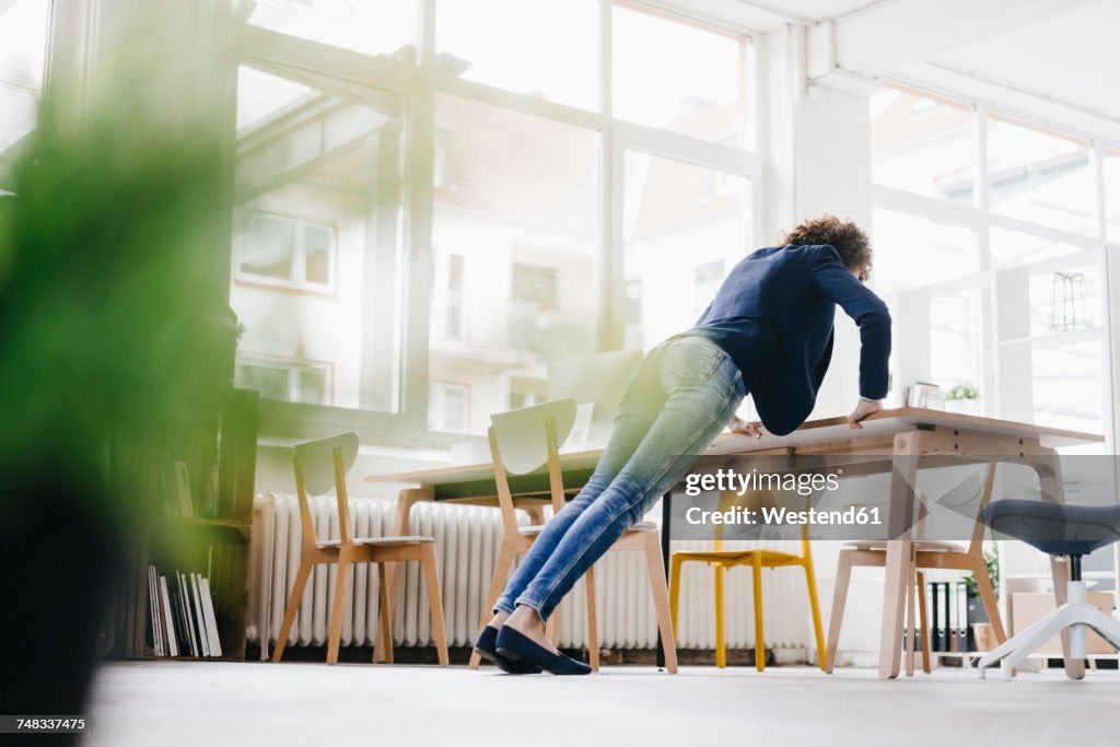 Businesswoman in office doing push ups on desk