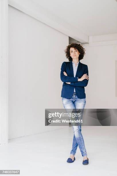 businesswoman standing in loft with arms crossed - business women pants stock-fotos und bilder