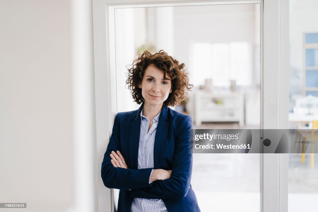 Businesswoman standing in her office with arms crossed