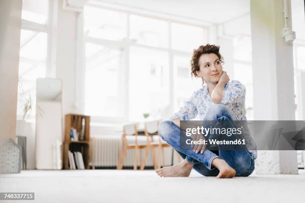 woman sitting on floor in her apartment - sitting on the floor stock-fotos und bilder