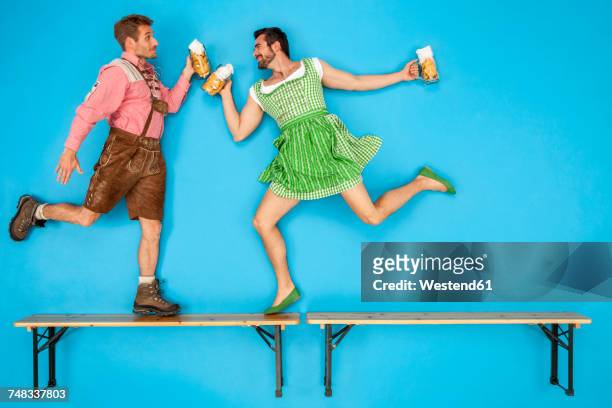 gay couple at the beer fest dancing on beer benches - oktoberfest fotografías e imágenes de stock