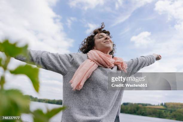 woman standing at lake pretending to fly - einzelne frau über 30 stock-fotos und bilder