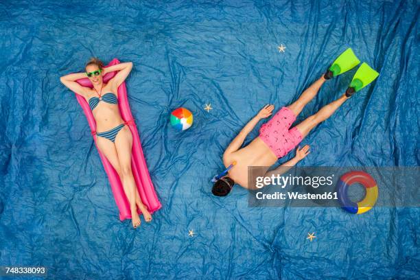 man snorkelling in the sea, while woman is relaxing on her airbed - luftmatratze von oben stock-fotos und bilder