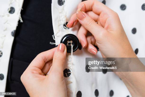 woman's hands stitching button on a dress, close-up - mani fili foto e immagini stock