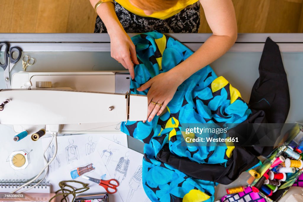 Fashion designer working with sewing machine, top view