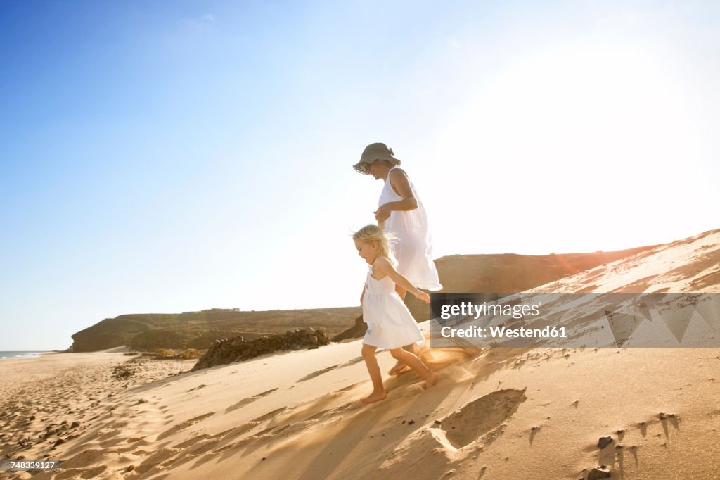 Spain, Fuerteventura, mother running with daughter on the beach