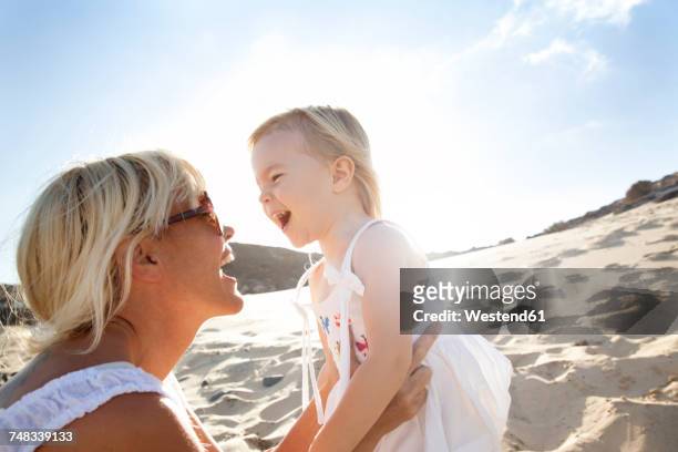 spain, fuerteventura, happy mother with daughter on the beach - eltern sonnenbrille sonne lachen stock-fotos und bilder