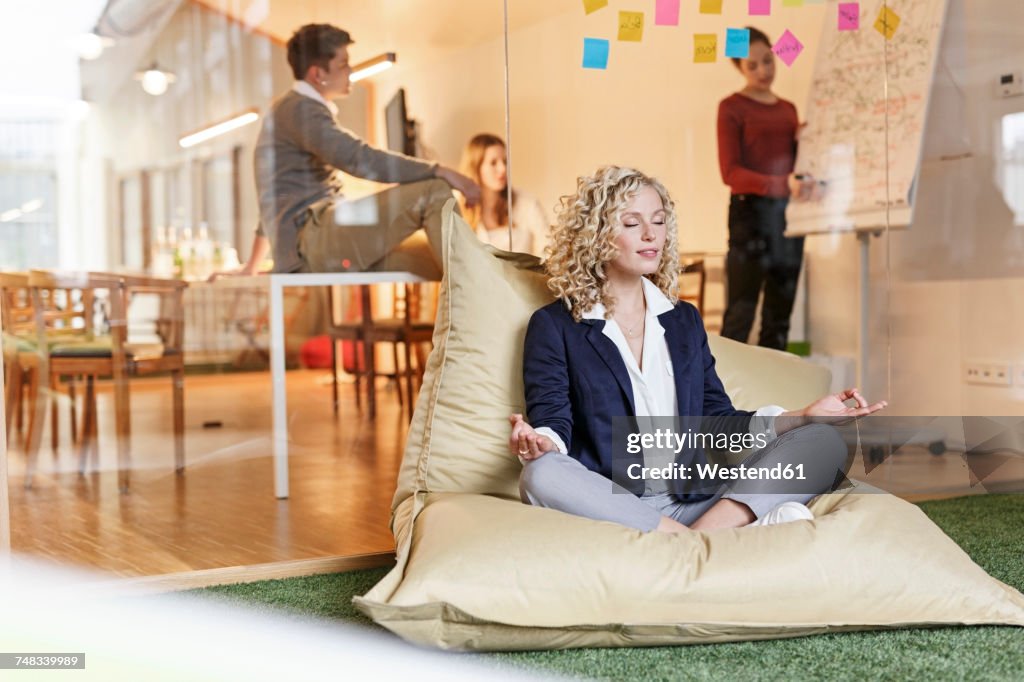 Woman doing yoga in bean bag with meeting in background