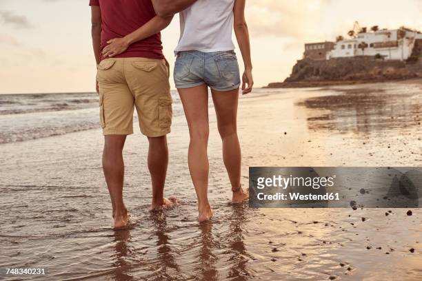 back view of couple in love walking at seaside - man touching womans leg fotografías e imágenes de stock