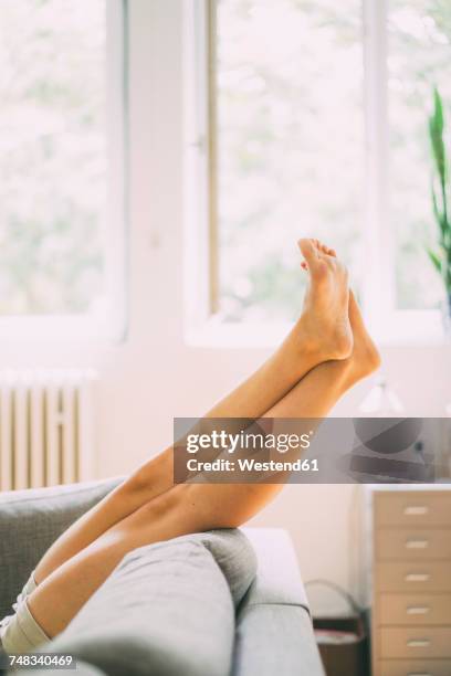 legs of woman lying on couch at home - beine stock-fotos und bilder