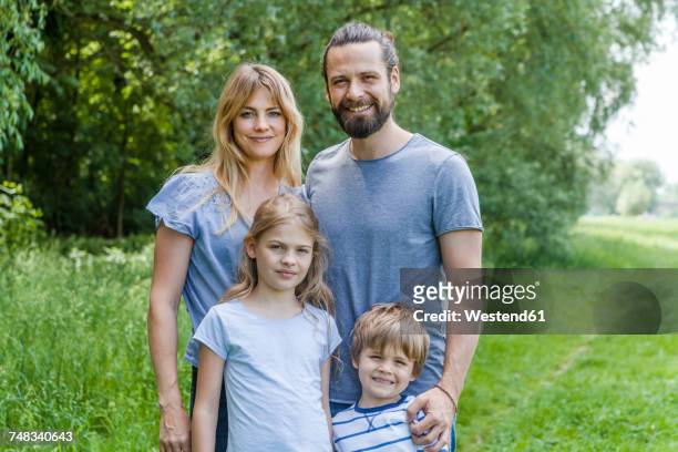 portrait of happy family standing on meadow - four people stock-fotos und bilder