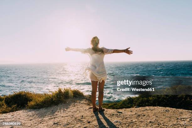 greece, cyclades, naxos, woman with raised arms standing at the sea at sunset - arms open stock pictures, royalty-free photos & images