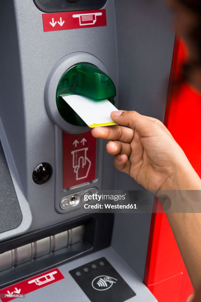 Hand of woman pushing credit card at cash dispenser, close-up