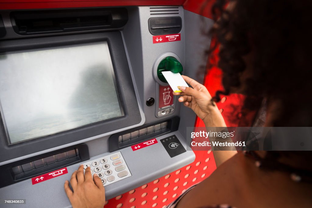 Woman pushing credit card at cash dispenser
