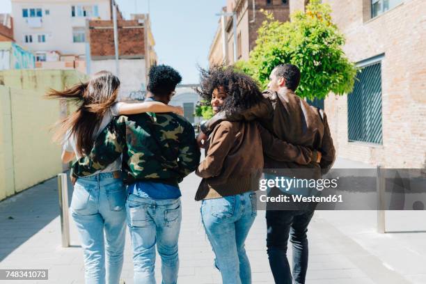 rear view of stylish friends walking on urban street - jeans back stockfoto's en -beelden