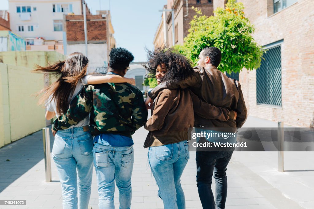 Rear view of stylish friends walking on urban street