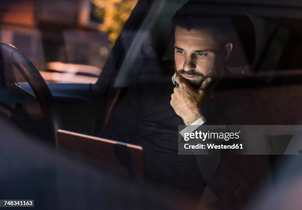 businessman with laptop in car at night - autonomous vehicles stock pictures, royalty-free photos & images