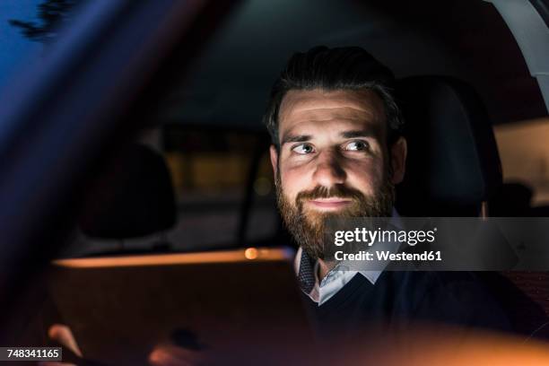 portrait of confident businessman in car at night - autonomo smartphone tablet fotografías e imágenes de stock