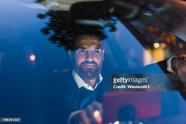 businessman using navigation device in car at night - business man car stock-fotos und bilder