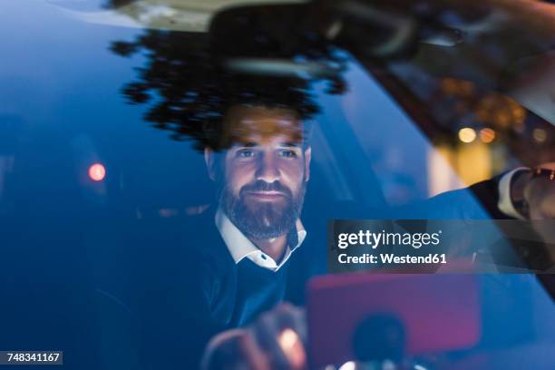 businessman using navigation device in car at night - driving a car at night stock pictures, royalty-free photos & images