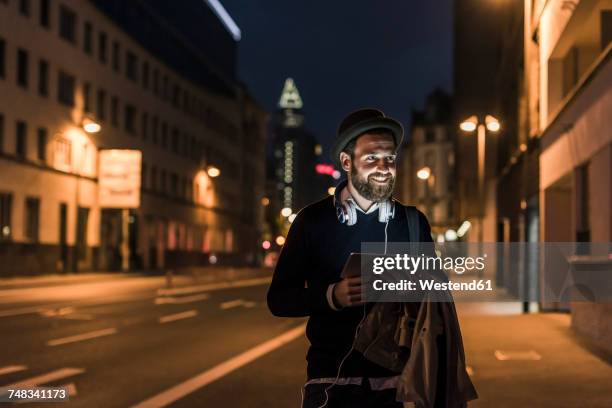 stylish young man with tablet on urban street at night - man business hipster dark smile stock pictures, royalty-free photos & images