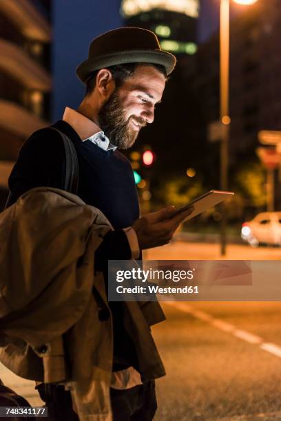 stylish young man with tablet on urban street at night - man business hipster dark smile stock pictures, royalty-free photos & images