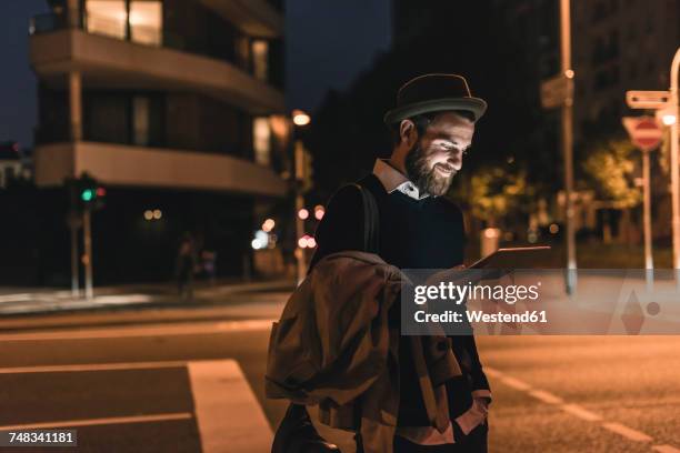 stylish young man with tablet on urban street at night - man business hipster dark smile stock pictures, royalty-free photos & images