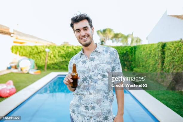 young man drinking beer at the poolside - beer luxury stock pictures, royalty-free photos & images