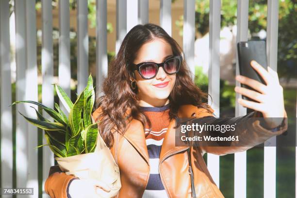 young woman carrying potted plant taking selfie with smartphone - sansevieria stock pictures, royalty-free photos & images