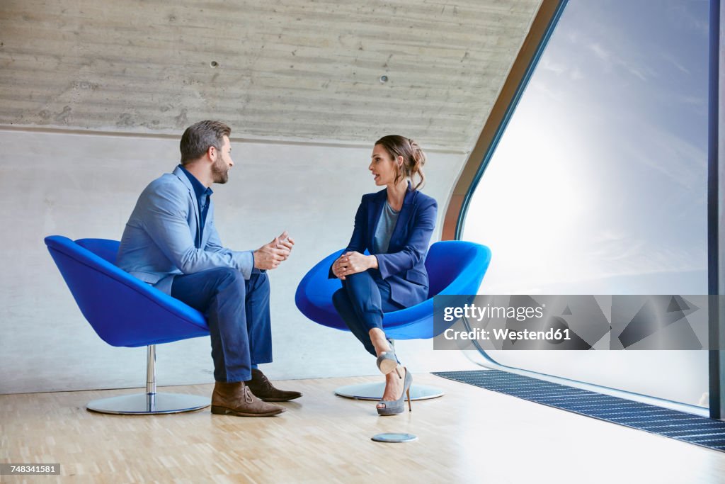 Man and woman sitting on chairs talking