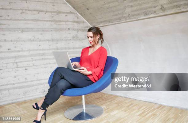 businesswoman sitting in chairusing laptop - red office chair stock pictures, royalty-free photos & images