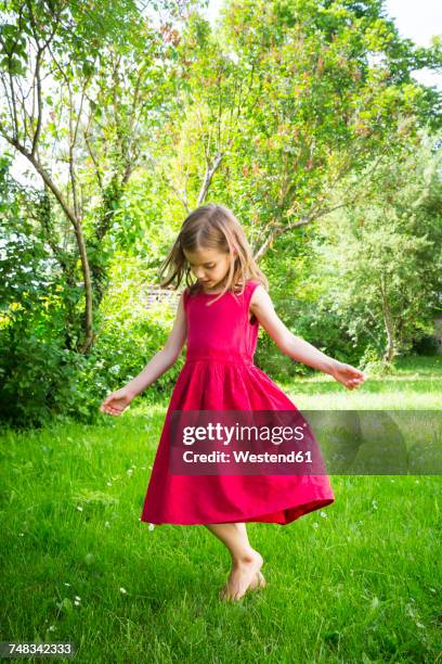 little girl wearing red summer dress dancing on a meadow - red dress ストックフォトと画像