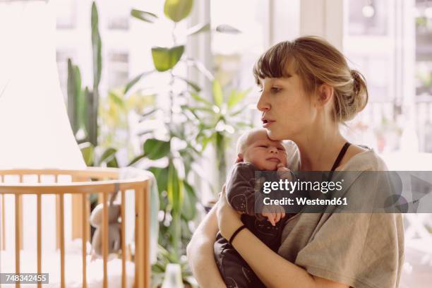 mother soothing and comforting her newborn baby boy at home - vida de bebé fotografías e imágenes de stock