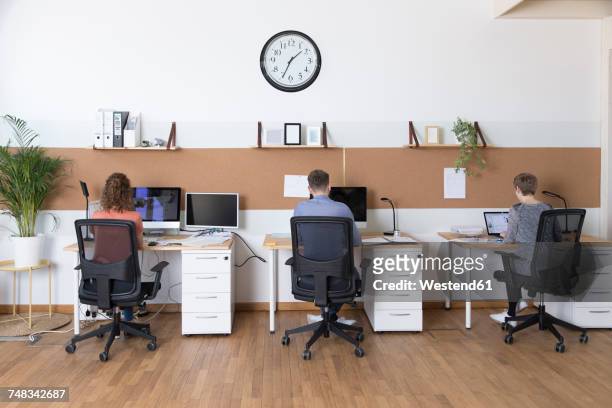 colleagues working in modern office - clock person desk stockfoto's en -beelden