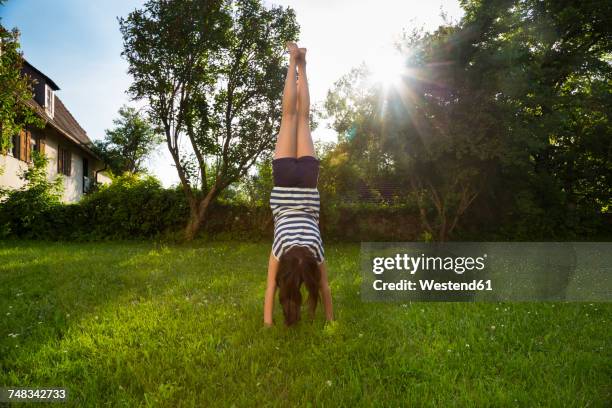 back view of girl doing handstand on a meadow - girls only brown hair barefoot foto e immagini stock