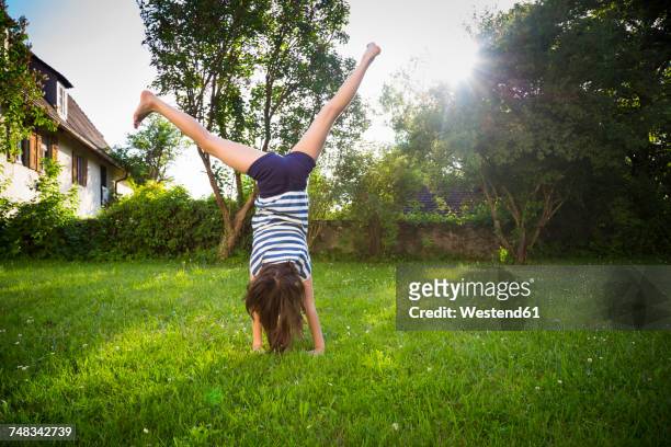 back view of girl turning cartwheel on a meadow - jardin de la maison photos et images de collection