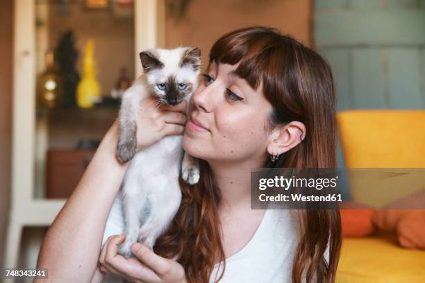 young woman with kitten at home - holding cat imagens e fotografias de stock