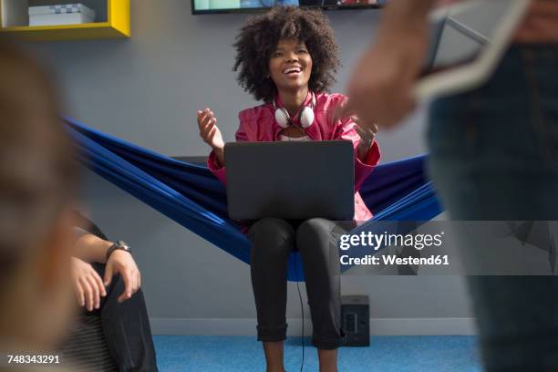 happy woman in hammock with laptop - colleagues in discussion in office conference room fotografías e imágenes de stock