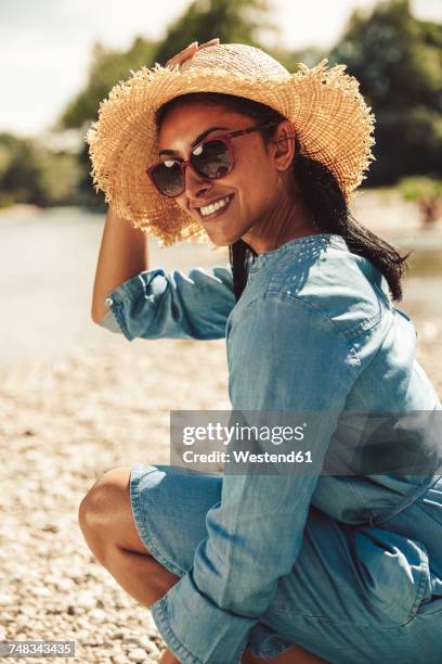 portrait of happy woman wearing straw hat and sun glasses on the beach - beach hut stock-fotos und bilder