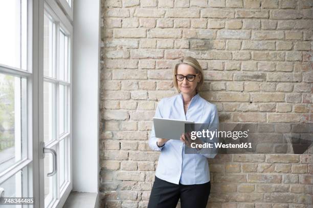 mature businesswoman using digital tablet - brick wall business person stock pictures, royalty-free photos & images