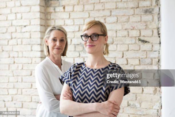 mature businesswoman working with younger colleague in office - zwei personen stock-fotos und bilder