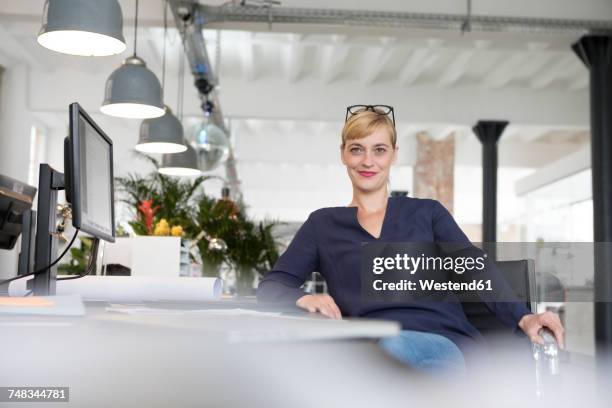 businesswoman sitting at desk - woman relaxed portrait sitting stock-fotos und bilder