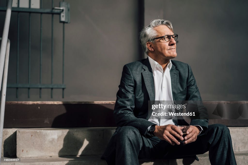 Senior businessman sitting on concrete stairs