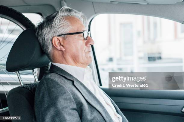 senior businessman sitting in car with closed eyes - sleeping in car stockfoto's en -beelden