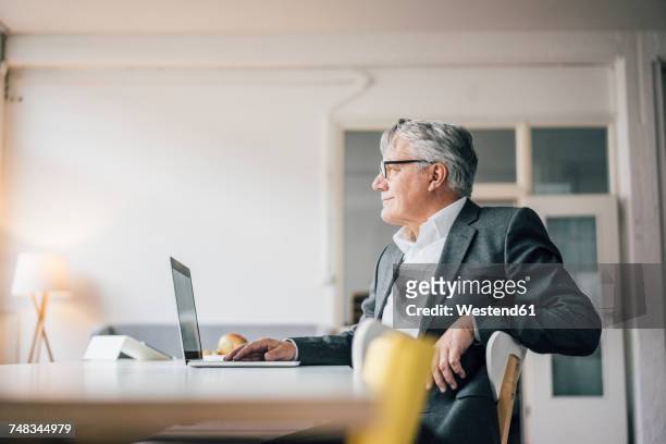 confident senior businessman using laptop - finanzwirtschaft und industrie stock-fotos und bilder