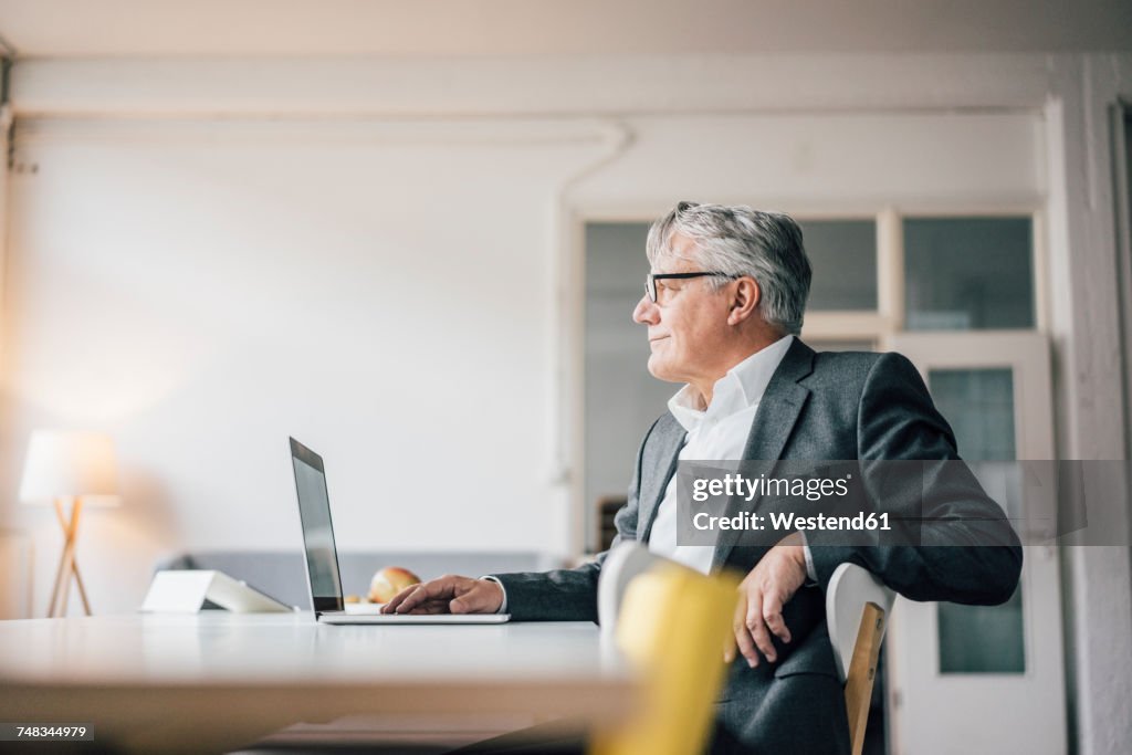 Confident senior businessman using laptop